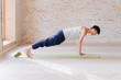 © yuliyalyashok - Relaxed young man doing yoga and meditating in studio