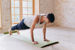© yuliyalyashok - Relaxed young man doing yoga and meditating in studio