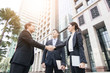 © khwanchai - cooperation and success concept, team of business people shaking hand with boss or leader outside for greeting and deal successful business project.