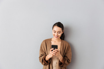 Poster - Portrait of a cheery young asian woman using mobile phone