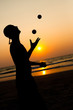 © Wallace - Silhouette of a man juggling balls on a beach at sunset