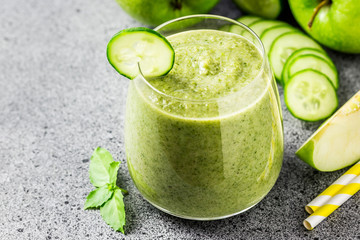 Refreshing summer cucumber green apple smoothie in a glass on concrete background. Selective focus, copy space.