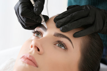 Wall Mural - Young woman undergoing procedure of eyebrow permanent makeup in beauty salon