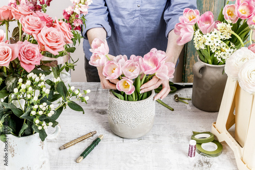 Cuadros en Lienzo Florist at work: woman arranging flowers. Bouquet of pink tulips.