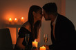 © Africa Studio - Young couple kissing while sitting at table with burning candles