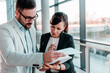 © bnenin - Businesswoman discussing documents with her male colleague at business meeting.