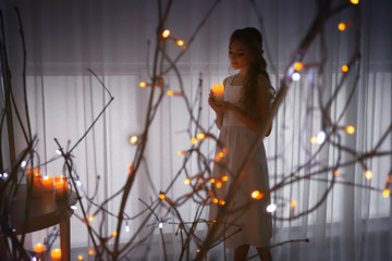 Wall Mural - Beautiful young woman holding candle at home