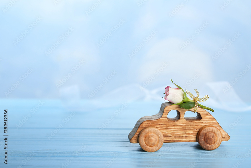 Decorative wooden car with beautiful rose on table