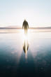 Man walks with his reflection following on a frozen lake in the Golden Circle in Iceland