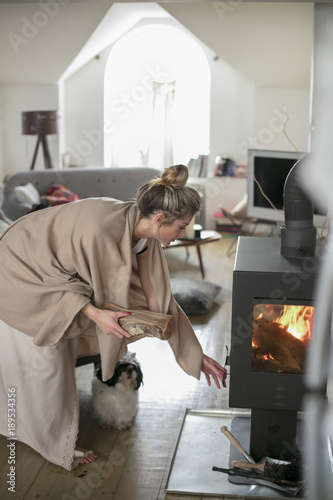 Beautiful Middle Aged Woman Inserts Wooden Logs Into The Fireplace