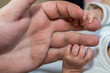 © Michael Eichhammer - Hand eines Babys greift nach Papas Fingern