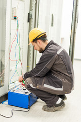 Wall Mural - electrician engineer tests system with relay test set equipment