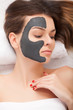 Beautiful Woman With Cosmetic Mask on Face. Girl Gets Treatment in Spa Salon against white Background