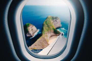 Wall Mural - airplane is flying over blue sea. tropical beach ocean landscape. view from plane window