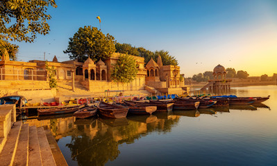Fototapete - Gadi Sagar (Gadisar) lake Jaisalmer Rajasthan with tourist boats and ancient architecture at sunrise.	