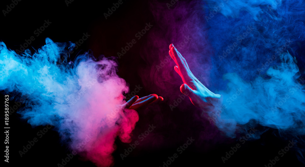 hands reaching from colorful smoke on black background - obrazy, fototapety, plakaty 