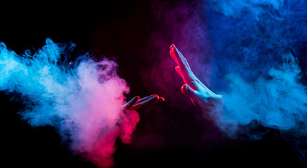 hands reaching from colorful smoke on black background