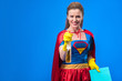 © LIGHTFIELD STUDIOS - portrait of woman in superhero costume and rubber gloves with rag and detergent isolated on blue