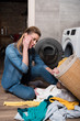 © LIGHTFIELD STUDIOS - emotional housewife looking at clothing before putting it into washing machine at home