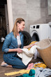 © LIGHTFIELD STUDIOS - smiling housewife taking clothing to put it into washing machine at home