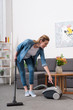 © LIGHTFIELD STUDIOS - attractive woman with vacuum cleaner cleaning room at home
