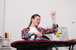 © LIGHTFIELD STUDIOS - low angle view of smiling woman listening music while ironing clothes at home