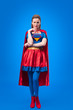 © LIGHTFIELD STUDIOS - thoughtful woman in superhero costume looking at camera isolated on blue