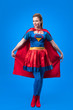 © LIGHTFIELD STUDIOS - attractive woman in superhero costume holding cape isolated on blue