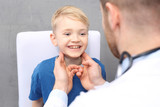 Chore dziecko u lekarza. Badanie lekarskie. Pediatra sprawdza węzły chłonne na szyi chłopca