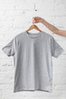 cropped image of woman holding grey shirt on hanger