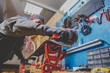 © Elizaveta - A man in work clothes, repairman in workshop ski service repairing the sliding surface of skis, Brushing, wax removal, final ski polishing. In the hands of an electric brush. Theme repair of ski curb