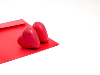 a red love letter envelope with two heart-shaped chocolate candies