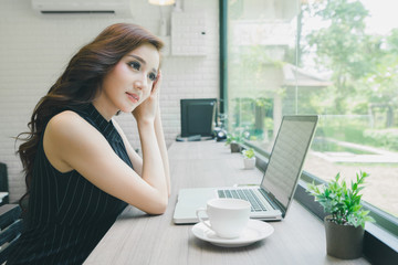 Tired young asian businesswoman working hard by laptop and drinking coffee in the coffee shop, headache from work