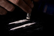 Drug addiction. Junkie man sniffs a line of cocaine through a dollar. Black background. Narcotics concept.
