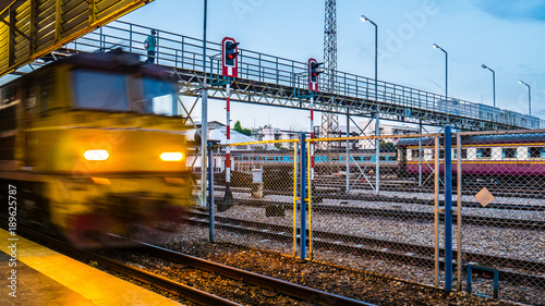 Zdjęcie XXL Pociąg jedzie po torach, a ludzie chodzą po moście kolejowym.