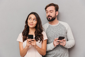 Poster - Portrait of a lovely young couple using mobile phones