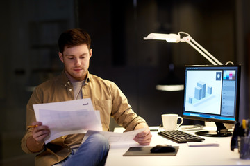 designer with papers working at night office