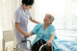 Asian young nurse supporting elderly patient disabled woman in using walker in hospital. Elderly patient care concept..