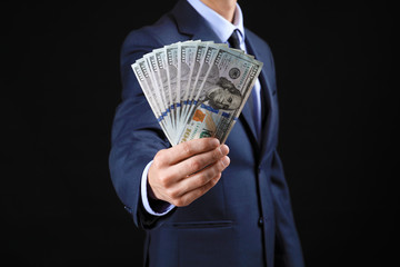 Wall Mural - Businessman with money on dark background. Corruption concept