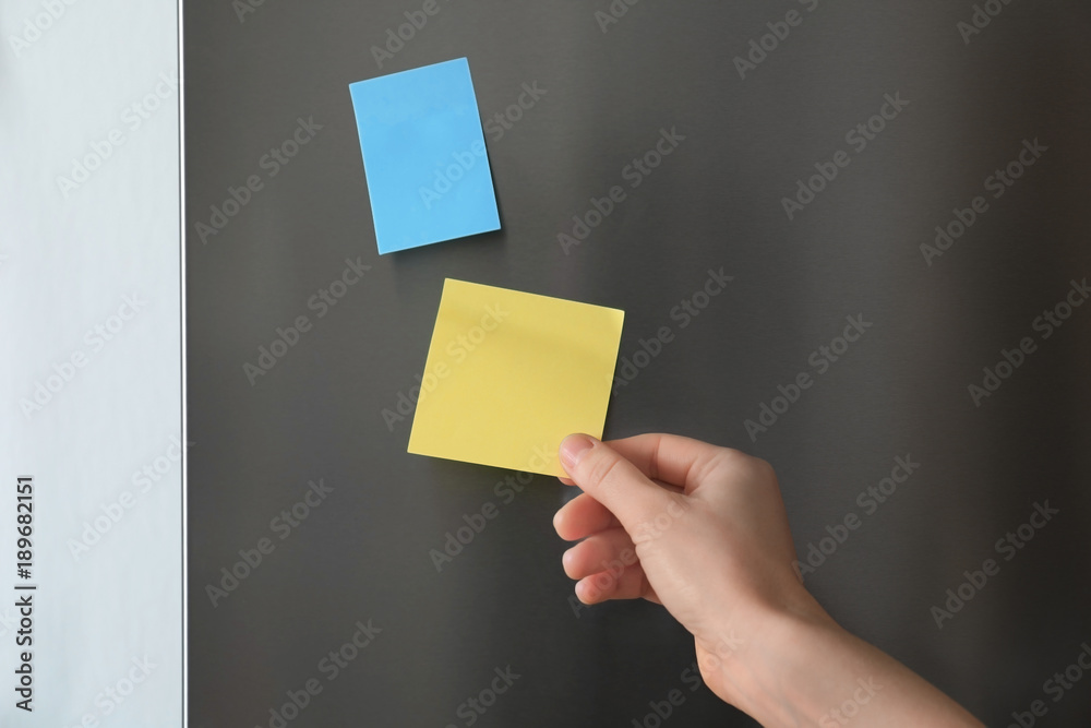 Woman touching paper sheet on refrigerator door