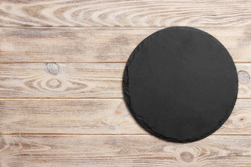 Poster - Black slate round stone on wooden background, top view, copy space