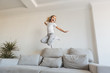 © LIGHTFIELD STUDIOS - smiling kid jumping on sofa and listening music with headphones
