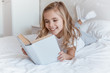 © LIGHTFIELD STUDIOS - smiling kid lying on bed and reading book