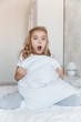 © LIGHTFIELD STUDIOS - surprised kid sitting on bed with pillow