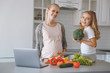 © LIGHTFIELD STUDIOS - happy pregnant mother and daughter with vegetables in kitchen