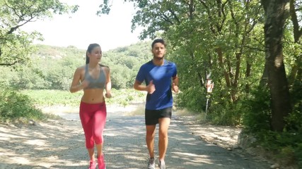 Wall Mural - beautiful young couple running sport fitness exercising together outdoor countryside forest