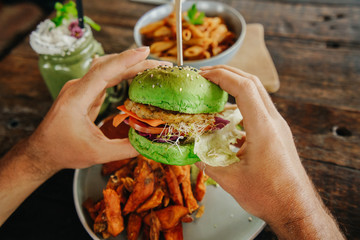 vegetarian green burger in the hands of a man. Healthy food. Modern useful fast food.