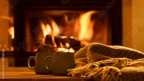 Fotografía Steam from a cups with a hot cocoa on the fireplace background.