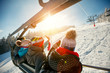 friends skiers and snowboarders on ski lift in the mountain at winter vacations