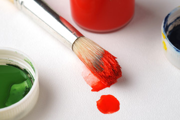 Brush with red paint close-up, canvas